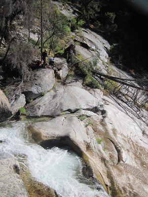 John, rigging a rappel next to a long waterfall.