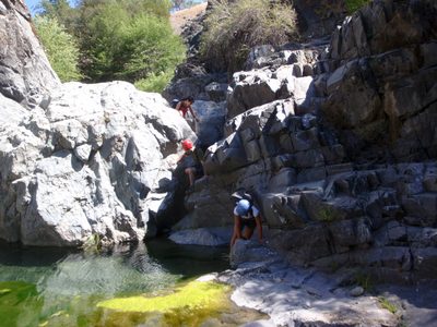 The crew scrambles over some boulders and through some...