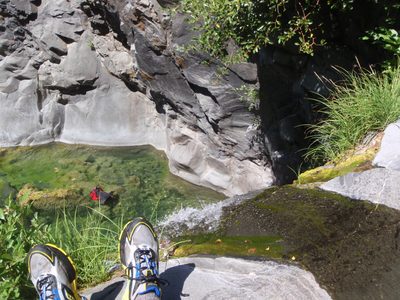 Chris's feet dangle over the edge of the first rappel.