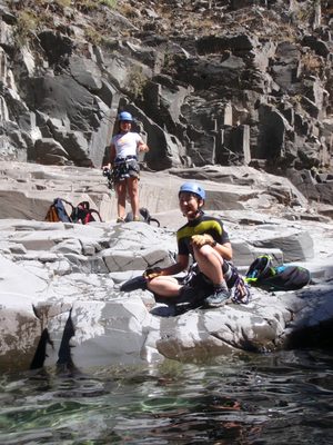 The girls watch the boys jump off rocks.