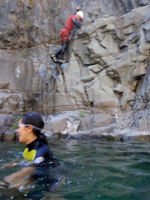 Monica in the pool while John climbs back to the jumping ledge.