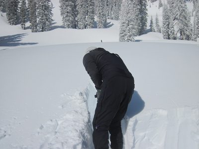 John digs a pit around a block of snow to perform a...