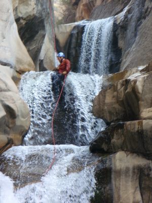 Joel, having fun rappelling through a high-flow waterfall.