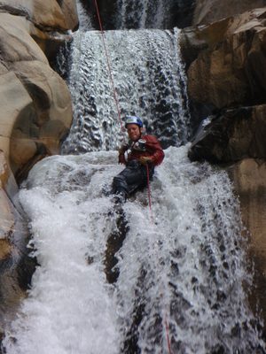 Joel, camera and all, rappelling through the waterfall.