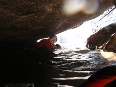 Following the river under a massive boulder.