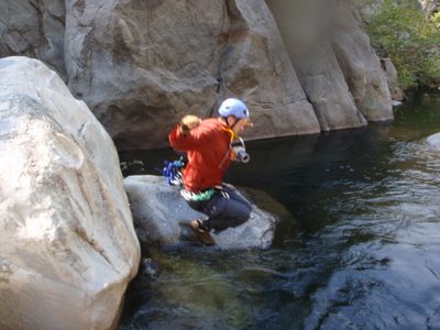 Joel jumping off a rock, camera around neck.  I am...