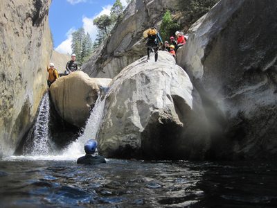 Monica rappelling down while others look on.