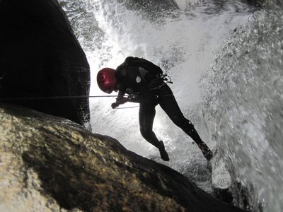 Aditi rappelling into the waterfall, wearing Vibram Five Fingers.