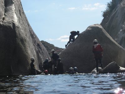 Monica carefully climbs up the boulder to reach the single bolt.