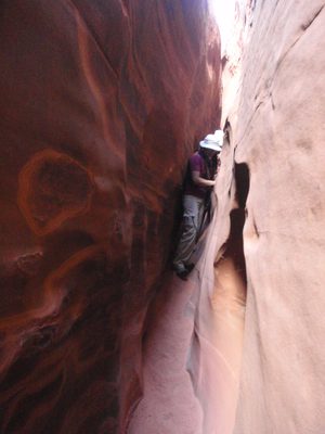 Turtle and Joel moving sideways through a narrow sandy slot.