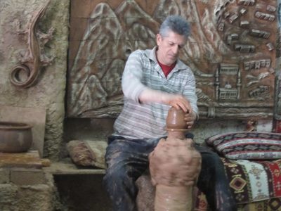 The potter kicked the wheel with his right foot as he...